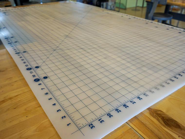 Large white plastic flexible cutting mat with blue numbers and grid lines.