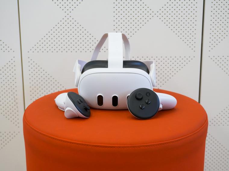 Meta Quest 3 headset sits with its two controllers on an orange surface.