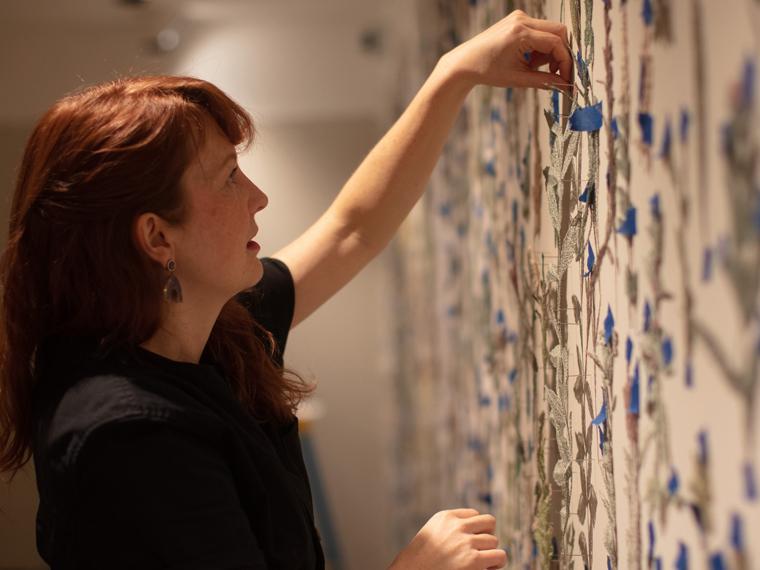 A photograph of artist Amanda McCavour installing her artwork in a gallery.