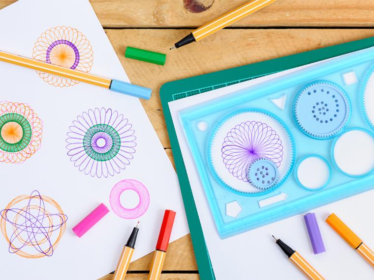 A photograph of spirograph drawings and and spirograph kit