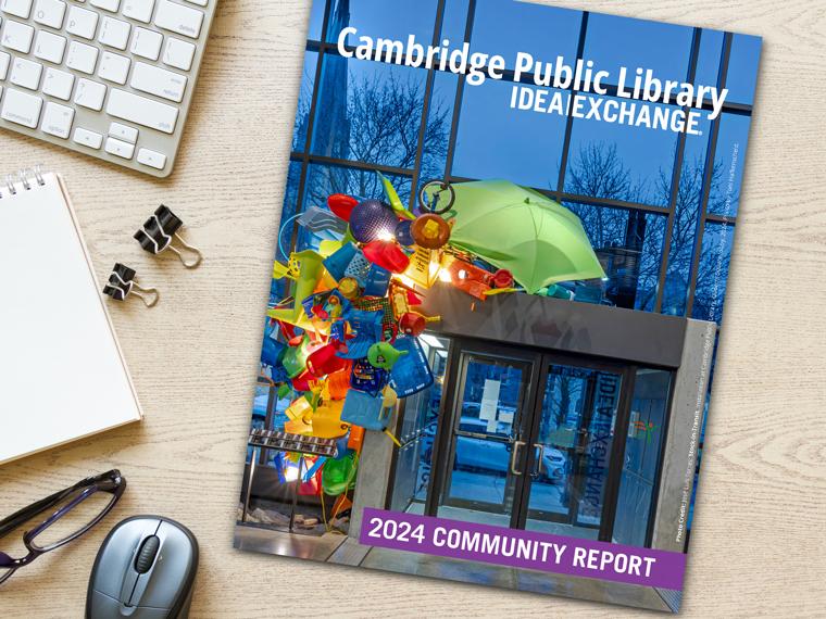 A copy of the 2024 Community Report sitting on a desk with a keyboard, notebook, and other office items.