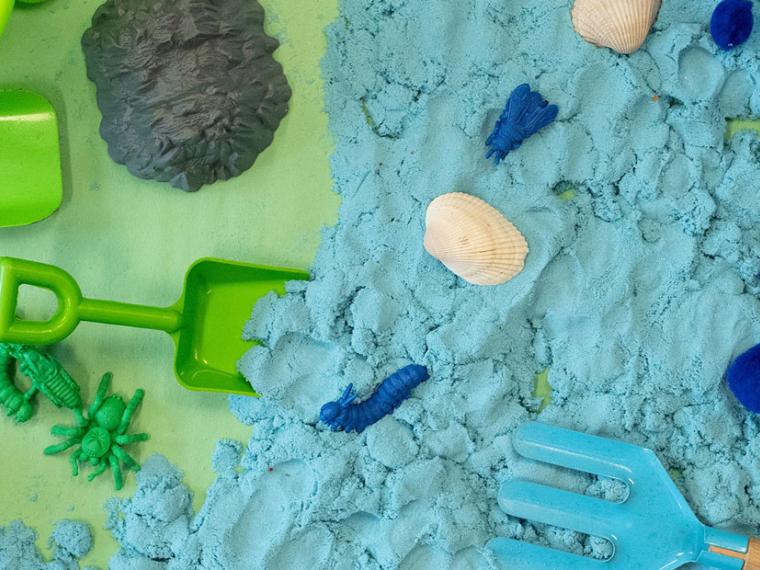 Garden toys, play clay, and other earth themed toys on a mat.