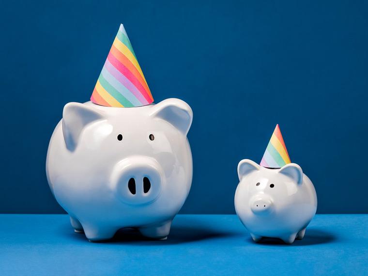 Two piggy banks wearing party hats, against a blue background