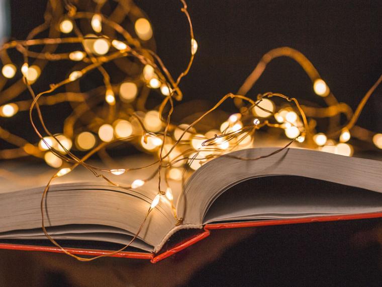 Front view and close-up of a book illuminated by lamps held by a librarian.