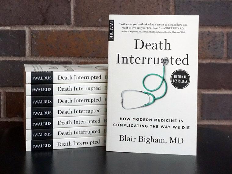 Copies of Death Interrupted: How Modern Medicine is Complicating the Way We Die by Blair Bigham in front of a brick wall.