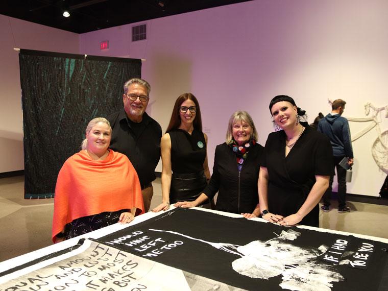 Representatives of Cambridge Public Library, Mary Misner, and artist Olivia Mae Sinclair stand behind It Takes Two on display in the Queen’s Square Gallery.