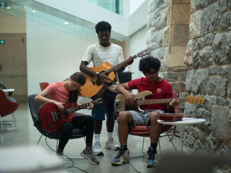 Three teens play musical instruments in the Old Post Office. 