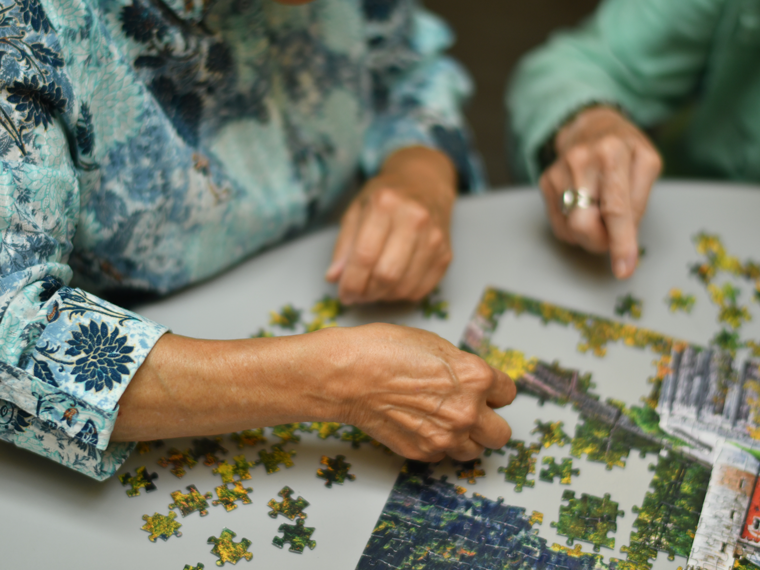 Hands of two people working on a puzzle. 