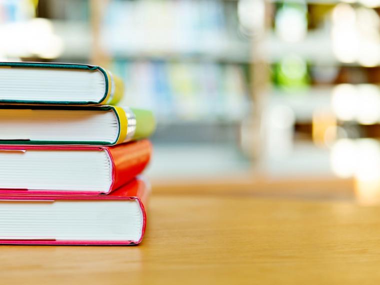 A stack of colourful library books on a table