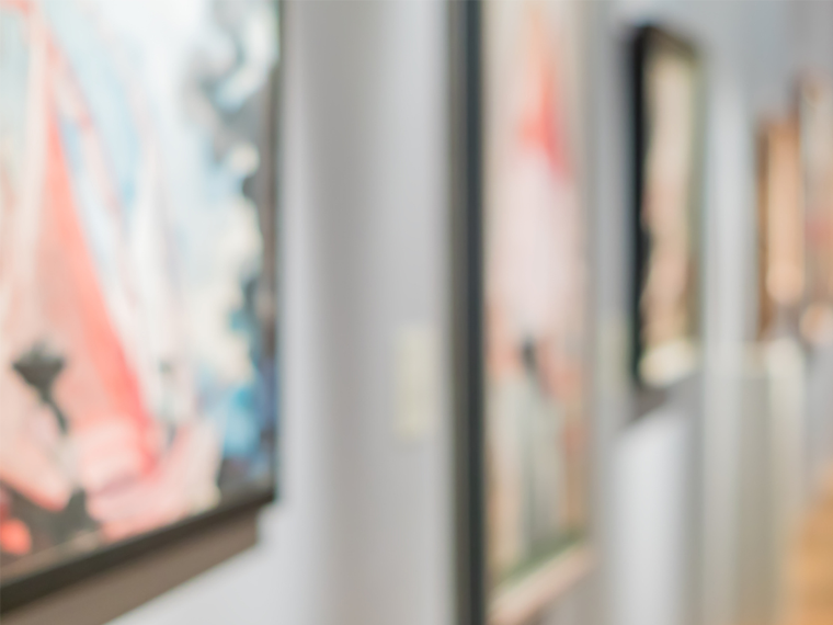 A blurred photo showing paintings hanging in a gallery