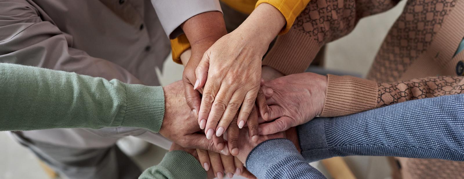 A top view photograph of senior people stacking hands in circle