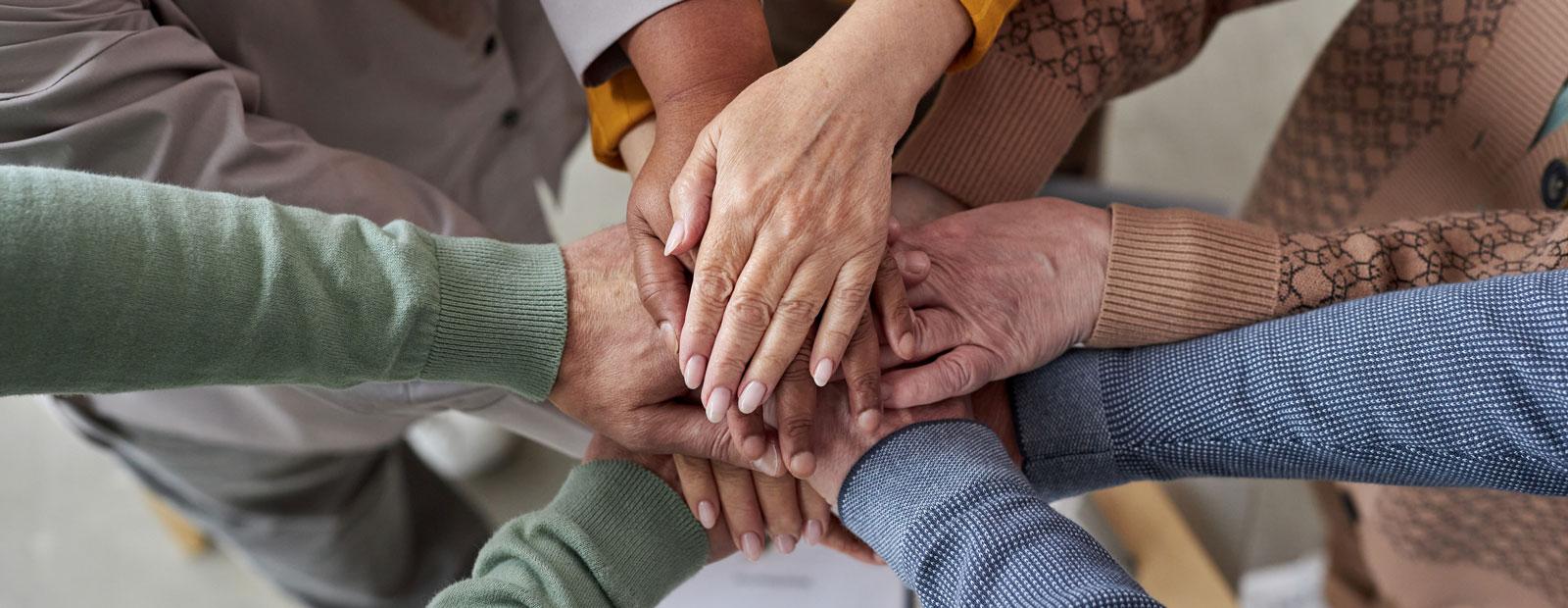 Top view closeup of older adults stacking hands in circle.