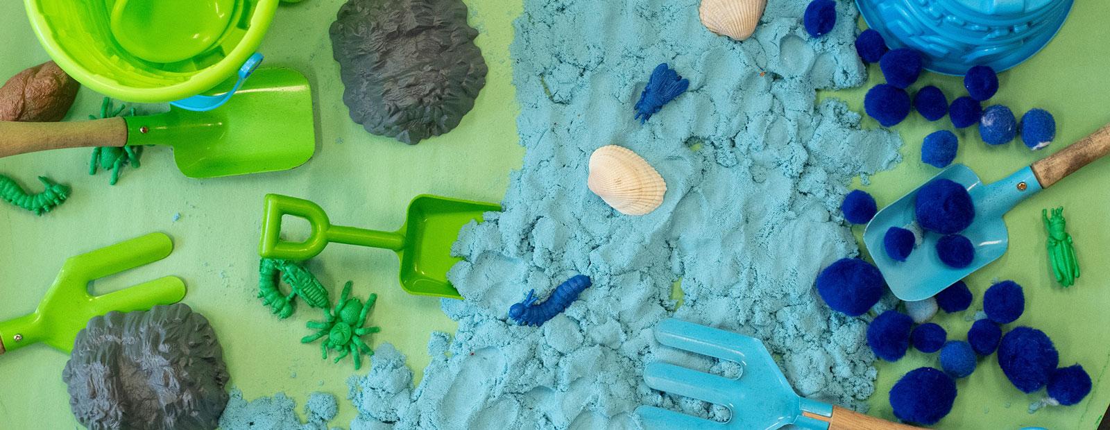 Garden toys, play clay, and other earth themed toys on a mat.