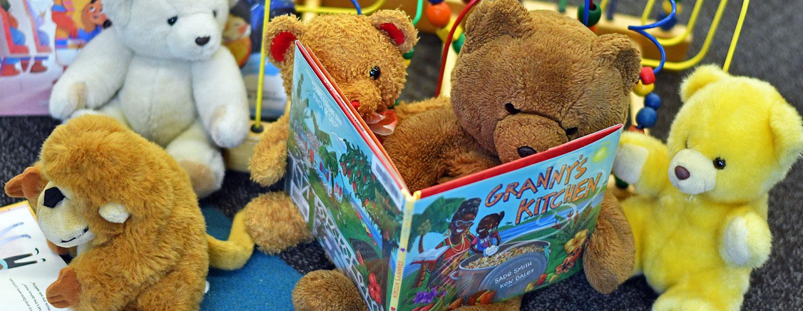 Group of teddy bears and other toys reading books together.