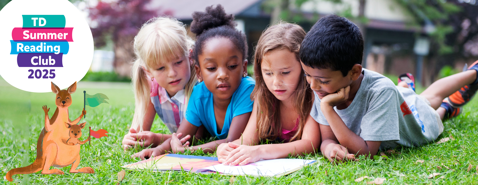 Four children read a book together on the grass in a park.