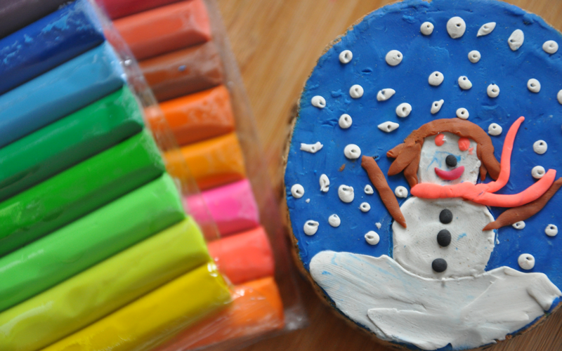 A close-up of a colourful Plasticine scene of a snowman.