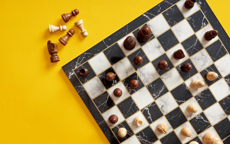 Chess board and pieces on yellow background.